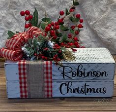 a wooden box that has some red berries on it and the words robin's christmas written in black