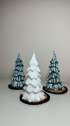 three small white christmas trees sitting on top of a table