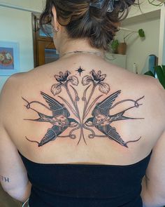 the back of a woman's shoulder with two hummings and flowers on it