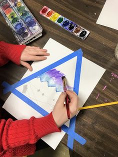 a child is painting with watercolors on paper