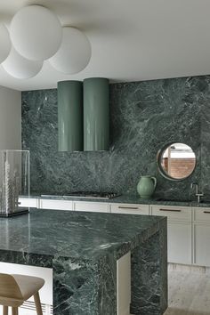 a kitchen with marble counter tops and white cabinets, along with a round mirror on the wall