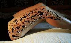 a woman laying on top of a bed next to a white wall with intricate carvings