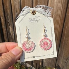 a pair of pink and white crochet earrings