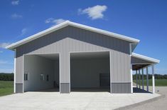 an empty garage in the middle of a large open field with grass and blue sky