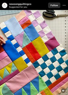 someone is making a colorful quilt with scissors and tape on the table next to it