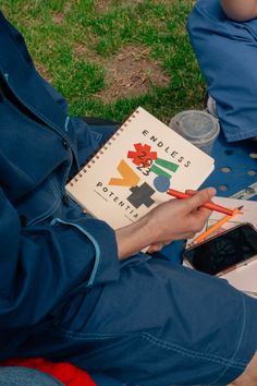 a person sitting on the ground with a book and cell phone in their hand,