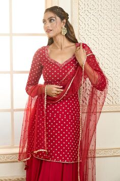 Red short kurta with polka dot pattern zari embroidery. Comes with embroidered border gharara and net dupatta.
Components: 3
Pattern: Embroidered
Type Of Work: Zari
Neckline: Leaf
Sleeve Type: Three Quarter
Fabric: Kurta and Gharara: Chiffon, Dupatta: Net
Color: Red
Other Details: 
Lace trims
Tassel edged dupatta
Back cutout kurta
Occasion: Wedding,Sangeet - Aza Fashions Festive Red Sharara With Bandhani Print, Red Fitted Sharara With Sheer Dupatta, Red Fitted Salwar Kameez With Sheer Dupatta, Fitted Red Dresses With Gota Work, Elegant Bandhani Print Sharara For Festive Occasions, Elegant Festive Bandhani Print Sharara, Red Fitted Churidar With Sheer Dupatta, Wedding Red Churidar With Bandhani Print, Festive Red Bandhani Print Churidar