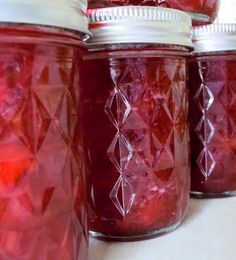 several jars filled with red liquid sitting on top of a white countertop next to each other