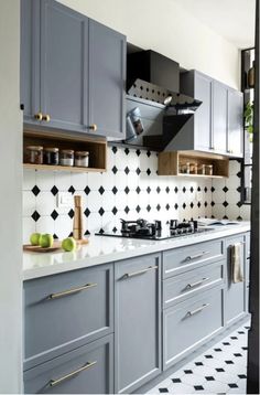 a kitchen with gray cabinets and black and white tiles