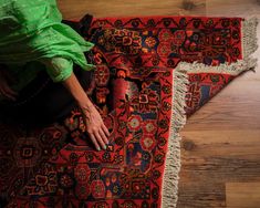 a woman sitting on top of a rug with her hand on the ground next to it