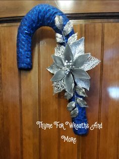 a blue and silver christmas wreath hanging on a wooden door with the words thye for weathers aid more