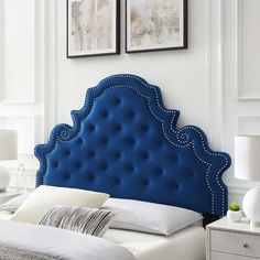 a blue headboard in a white bedroom with two pictures on the wall above it