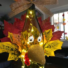 a lighted wine bottle with a turkey head on it and fall leaves in the background