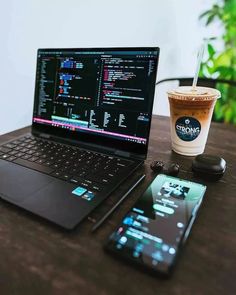 an open laptop computer sitting on top of a wooden table next to a cup of coffee