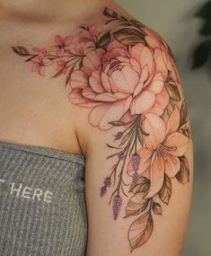 a woman's shoulder with pink flowers and leaves on her left arm, which has the word here written below it