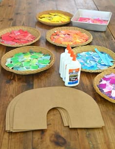 paper plates are arranged on a wooden table with paint and craft supplies in the middle