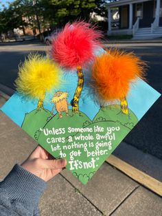 someone holding up a book with two pom poms on it