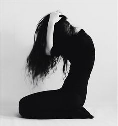 a woman with long hair sitting on the ground