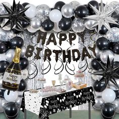 a happy birthday party with balloons, cake and wine bottle in front of a backdrop