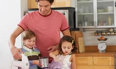 a man standing next to two children in a kitchen with an electric blender on the counter