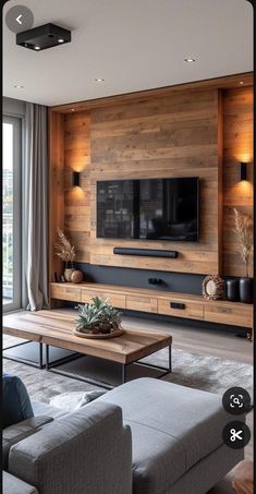 a living room with couches, tables and a television on a wooden paneled wall