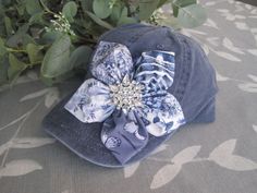 ALL ORDERS TOTALING OVER $35 SHIP FREE I designed this blue navy  trucker baseball cap making an adorable coordinating fabric petal flower. I added a beautiful all rhinestone accent to the center of the flower.  This hat is so pretty. See more of my  hats here: http://www.etsy.com/shop/theraggedyrose?section_id=10557807 CUSTOM ORDERS ALWAYS WELCOME.... Will ship in 1 to 2 business days after payment is received.  Thanks for taking the time to stop by and look at my little shop. Hope you enjoyed. Upscale Clothes, Bling Hats, Painted Hats, Hats Baseball, Summer Hats For Women, Flower Hat, Petal Flower, Cap Designs, Fabric Roses