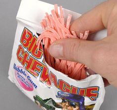 a hand is holding a bag of chewing gummy candies with toothpicks in it