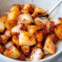 a white bowl filled with potatoes covered in cinnamon