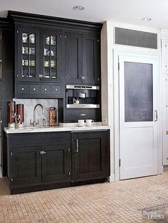 a kitchen with black cabinets and marble counter tops, along with a chalkboard on the wall