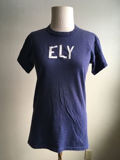 "1960s crew neck t-shirt Russell Southern Company cotton made in USA blue white ELY lettering sewn on authentic age wear faded, light pilling, soft label size L (see below) measures, lying flat, shoulder-17\" sleeve-5 1/2\" chest-18\" length-27\"" Navy Pre-shrunk Cotton T-shirt, Vintage Navy Cotton T-shirt, Retro Cotton Crew Neck T-shirt, Navy Cotton T-shirt With Letter Print, Pre-shrunk Navy Cotton T-shirt, Navy Cotton Pre-shrunk T-shirt, Soft-washed Cotton Vintage T-shirt, Vintage Crew Neck Top With Text Print, Vintage Blue Crew Neck T-shirt