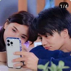 a man and woman are looking at their cell phones while laying on the table together