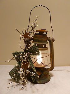 an old fashioned lantern with flowers in it on a white table cloth covered tablecloth