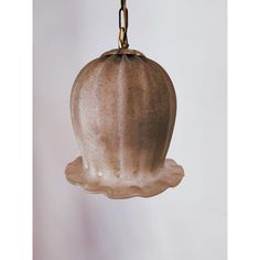 a brown glass hanging light fixture with a gold chain on the end and a white wall in the background