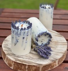 a candle with lavender on it sitting on a wooden table next to a piece of wood