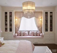 a bedroom with a window seat and chandelier in the corner, along with built - in bookshelves