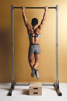 a man hanging upside down on a pull up bar in front of a yellow wall