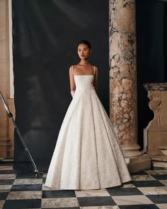 a woman in a white wedding dress standing next to a black and white checkered floor