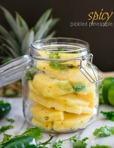 pineapple pickles in a glass jar on a table with green peppers and limes