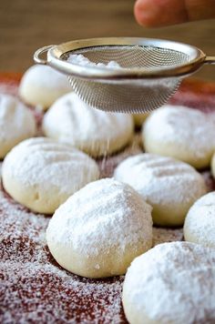 powdered sugar cookies are being grated onto a baking sheet with a strainer