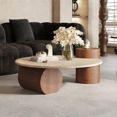 a living room with a couch, coffee table and flowers in a vase on the floor