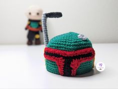 a crocheted boba fett hat with a toy behind it