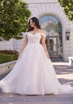 a woman in a wedding dress is walking down the street with her hand on her hip