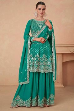 The Teal Green Chinon Silk Bridal Sharara Suit features traditional embroidery of zari, resham thread, and sequence work on the peplum style anarkali top. Accompanied by a chinnon silk sharara bottom and dupatta, this suit exudes elegance and intricate designs.    Top Length: 36"  Sleeves: 21"  Bottom Length: 42"  Embroidered, zari, resham thread, and sequence work   Elastic waist band  Fully Stitched with lining 3 piece suit   Dry clean    Fit:     True to size   Inside Margin:   1.5" inch on b Bridal Sharara Suit, Bridal Sharara, Silk Sharara, Designer Sharara Suits, Anarkali Tops, Gharara Suits, Sharara Suit, Silk Bottoms, Designer Salwar Suits