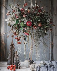 a vase filled with flowers and plants on top of a wooden table next to other decorations