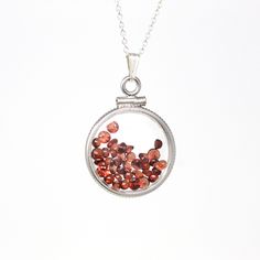 "Timeless handcrafted modern sterling silver genuine garnet shaker locket! This classic pendant is dime sized with coin style bezels, and clear lucite covers. The round charm hangs from a brand new sterling silver, and is filled with approximately 2.5 carats of round & cabochon cut faceted genuine garnet gemstones. An incredible piece of brand new gemstone jewelry, featuring January's birthstone! ERA - Brand New METAL / MATERIAL - Sterling silver locket & chain, lucite clear covers, 1 sc Locket Chain, January Birthstone Jewelry, Sterling Silver Locket, Silver Locket, Pendant Bails, Logo Gifts, Garnet Jewelry, January Birthstone, Silver Lockets