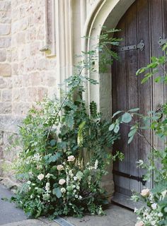 an old door is surrounded by greenery and flowers