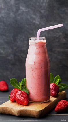 a smoothie with strawberries on a cutting board