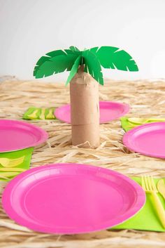 pink plates and palm tree on wicker table cloth with green napkins, yellow forks and utensils