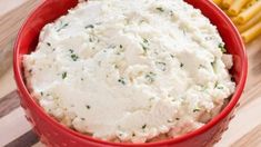 a red bowl filled with mashed potatoes on top of a wooden table