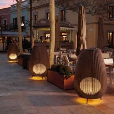 an outdoor dining area at dusk with tables and umbrellas in the sun set up